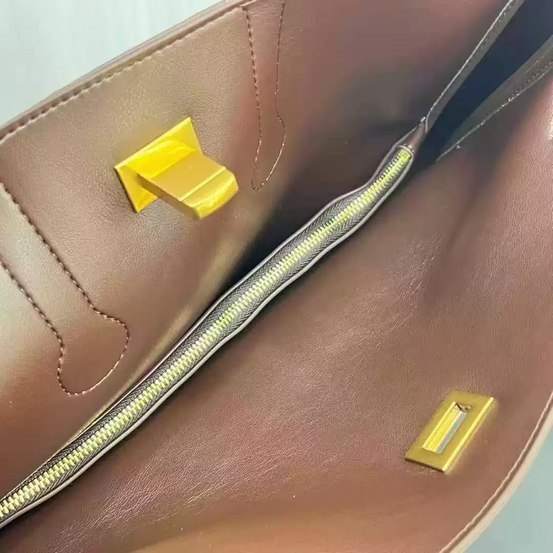 Close-up of a brown leather bag with gold zipper and hardware.