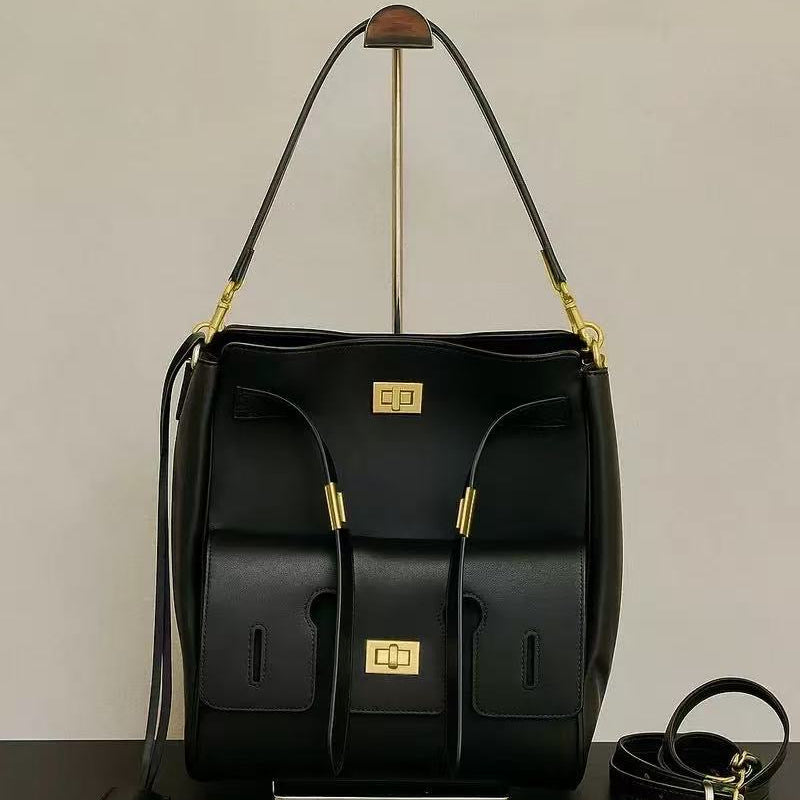 Black leather bag with gold accents on a black surface and beige background