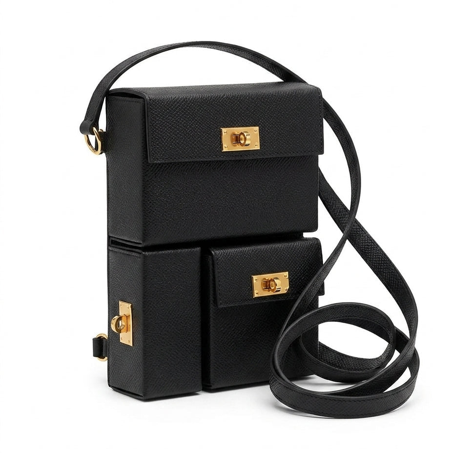 A black textured leather crossbody bag with a unique stacked box design and gold-tone hardware, shown on a plain white background.