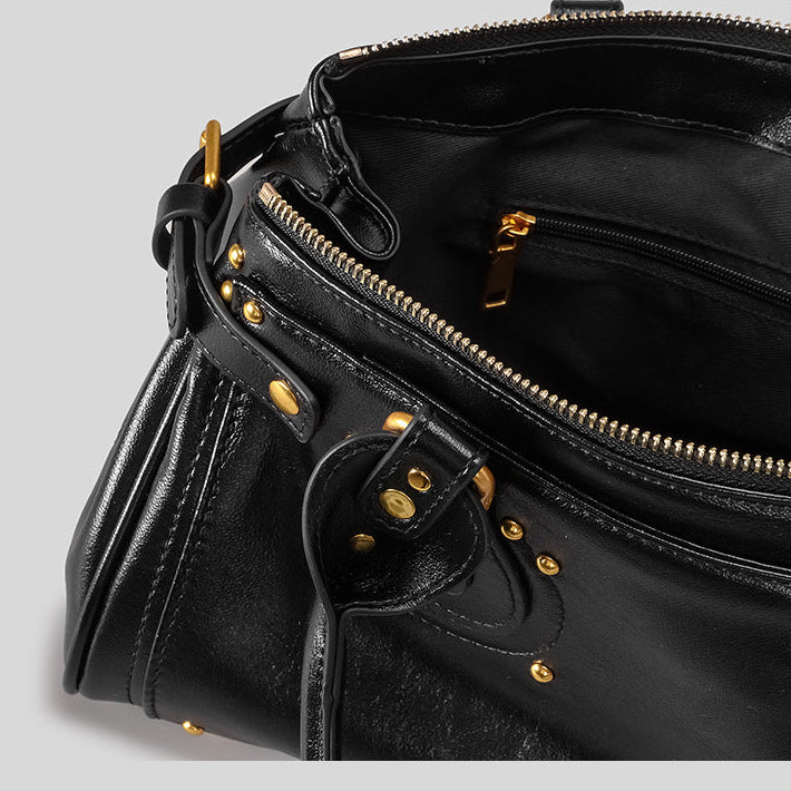 Black leather handbag with gold accents on a light gray background