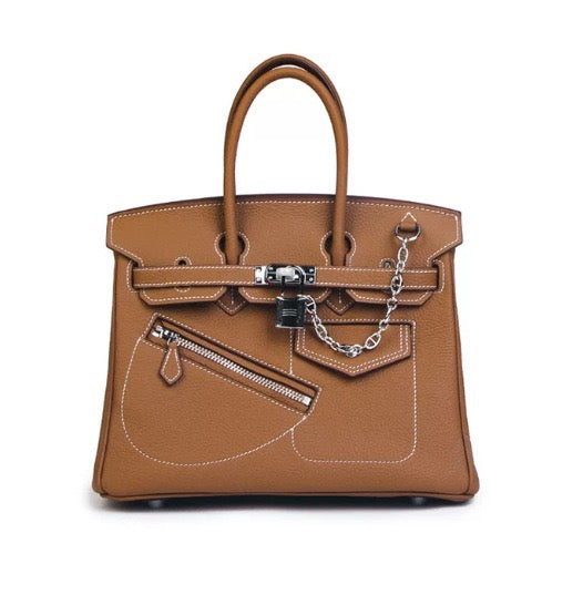 A structured tan leather handbag with double top handles, silver-tone hardware, a front zip pocket, and a decorative chain detail, photographed against a plain white background.
