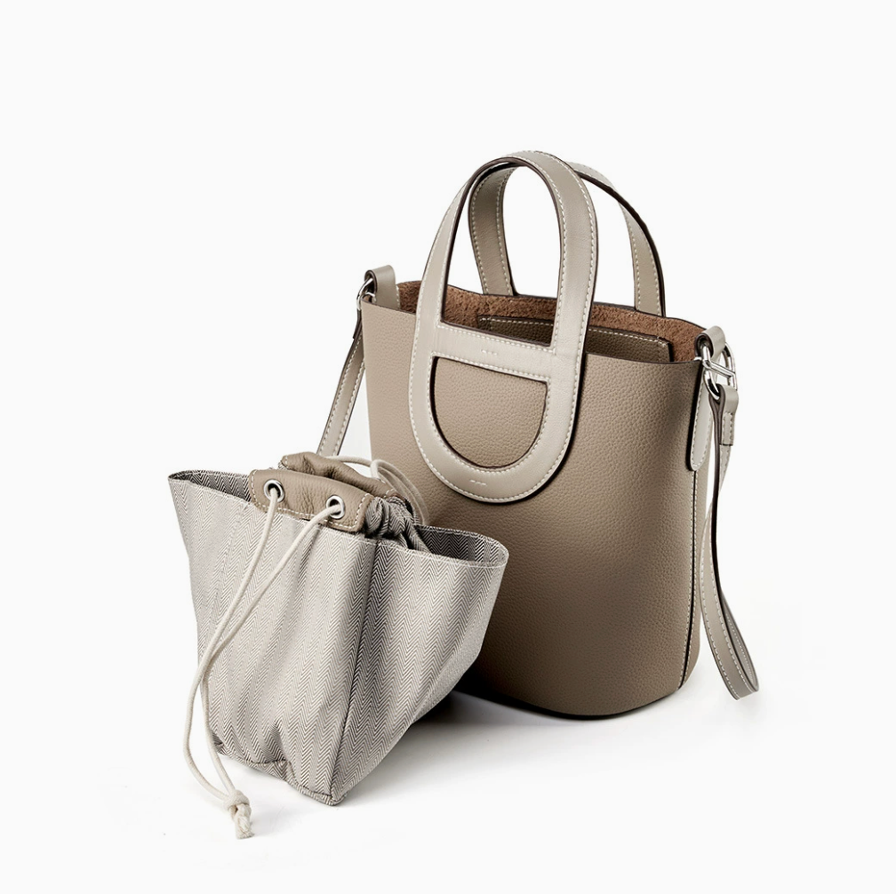 Two bags, a larger beige handbag and a smaller gray drawstring bag, on a white background.