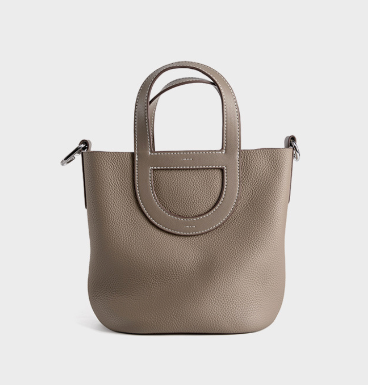 Beige handbag with a circular handle on a light gray background