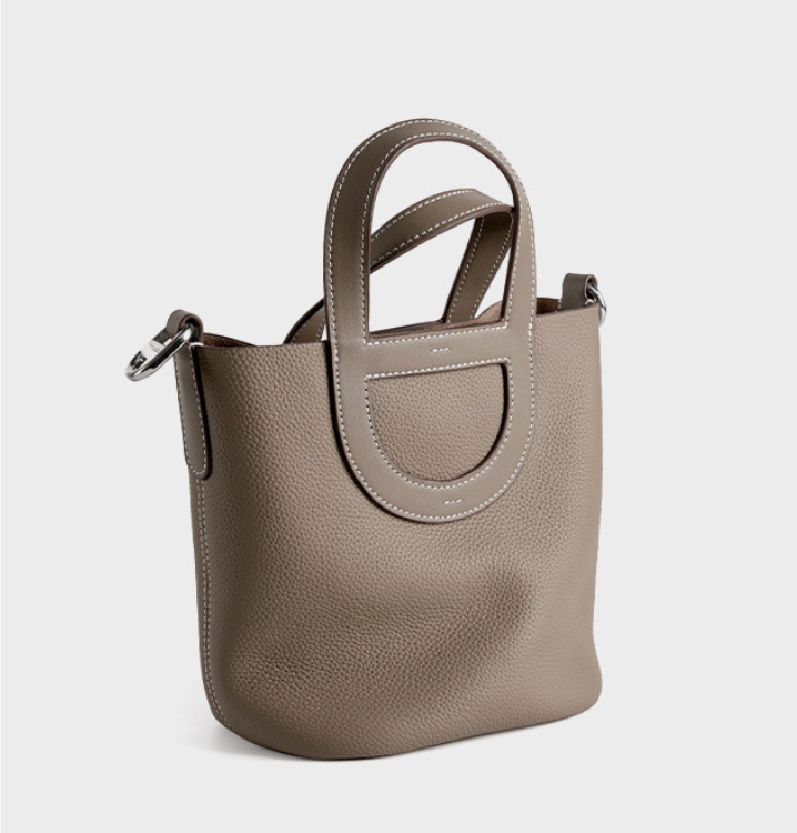 Gray handbag with a circular handle on a light gray background