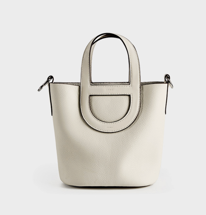 White handbag with a circular handle on a light gray background