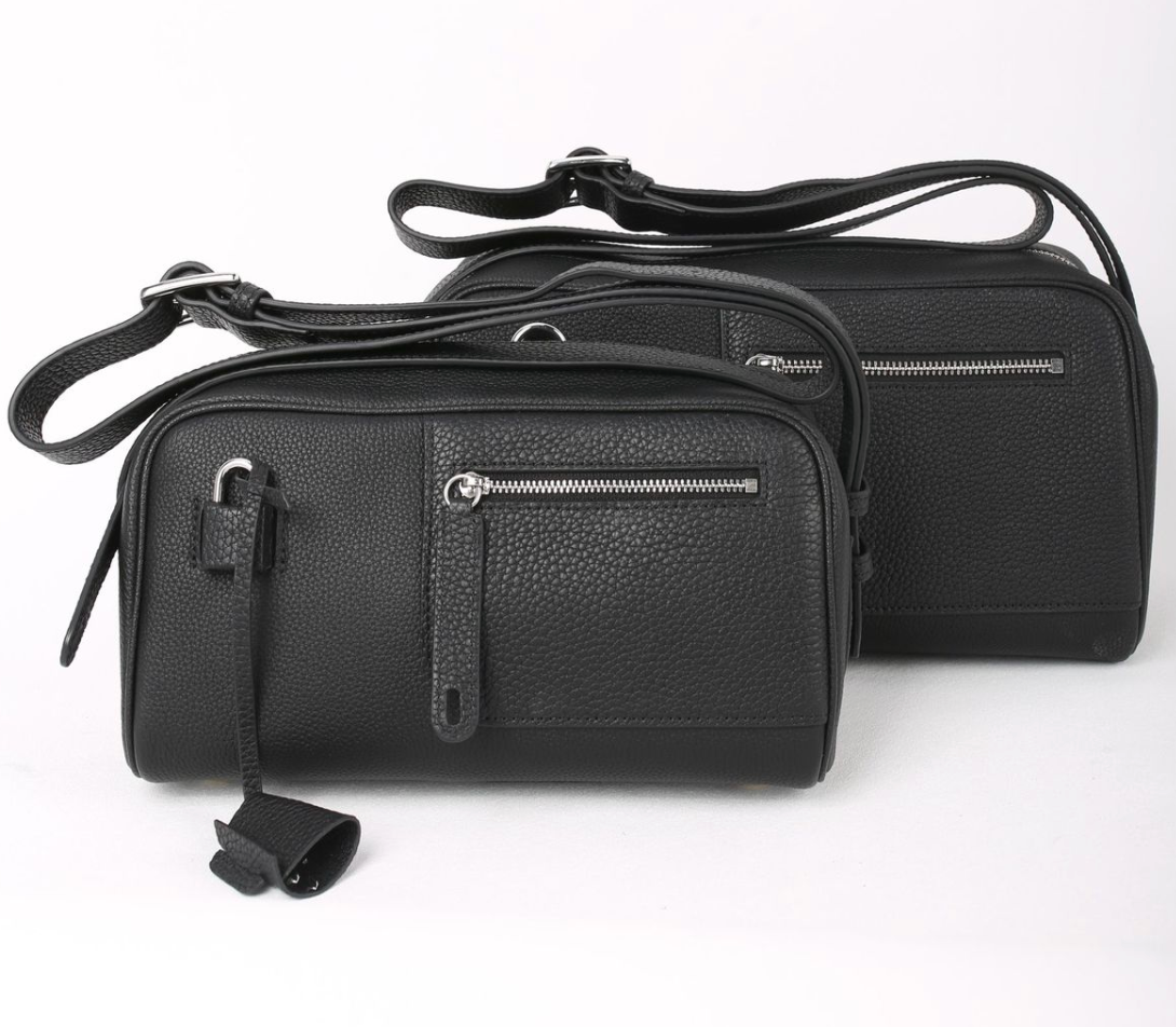 Two black leather handbags with zippers on a white background