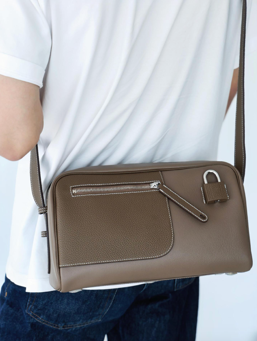 Brown leather shoulder bag with a lock on a white background