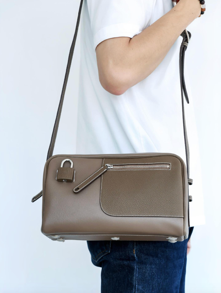 Person holding a brown leather handbag against a white background