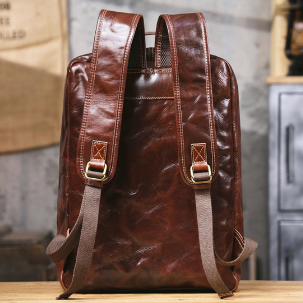 Brown leather backpack on a wooden surface with a blurred background