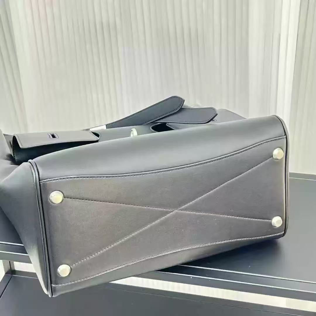 Gray leather handbag with gold studs on a reflective surface