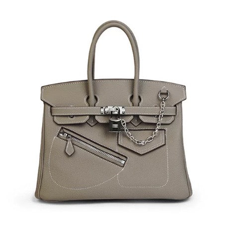 A taupe leather handbag with silver-tone hardware, dual top handles, a front zip pocket, and a decorative chain detail, shown against a plain white background.