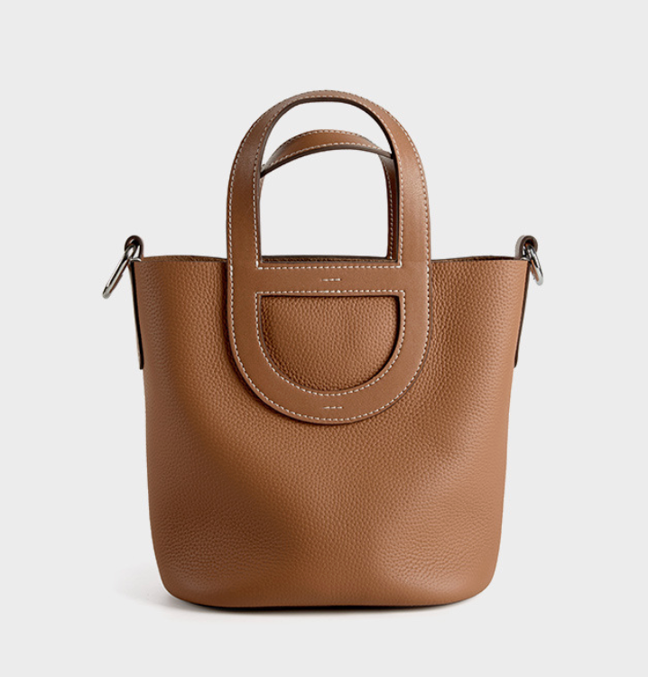 Brown leather handbag with a handle on a light gray background
