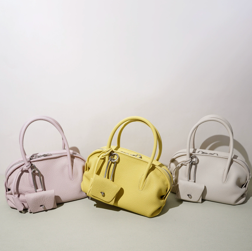 Three handbags in pink, yellow, and white on a light gray background