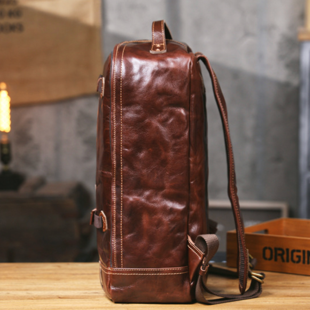 Brown leather backpack on a wooden surface with a blurred background